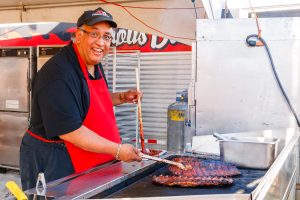 Photo by Rick Pepper - 2013 RibFest in Riverfront Park, Mankato - "Famous" Dave Anderson adding a final touch as ambassador for Famous Dave's