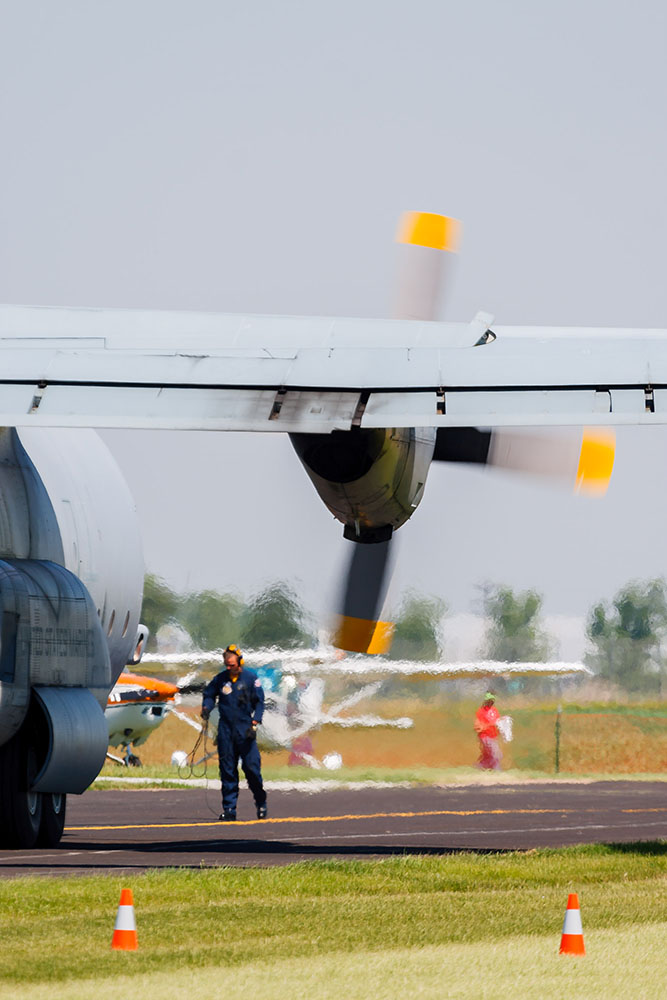 Photo by Rick Pepper - 2012 Mankato Air Show - The maintenance C-130 Hercules - Ground personnel can be seen through the distortions created by the extremely high-temperature turbine exhaust. Normally "Fat Albert" (also a C-130, painted in a matching color scheme) travels as part of the Blue Angels to transport maintenance equipment. During this particular time it was being serviced and a substitute Marine C-130 was being used, so there was no JATO short-takeoff demonstration.