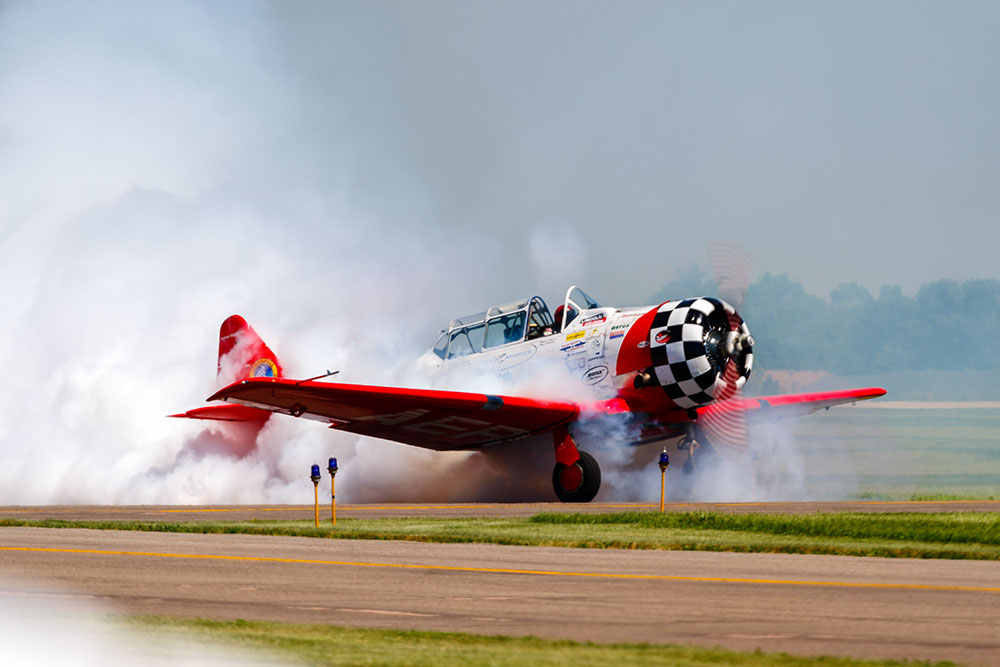 Photo by Rick Pepper - A T-6 Texan belonging to the Shell Aerobatic team smokes it up before take-off.