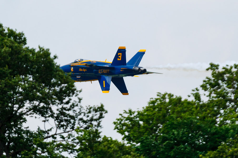 Photo by Rick Pepper - 2012 Mankato Air Show - Blue Angel aircraft 1-4 (1 and 3 in view) clear the tree tops approaching the airshow in the diamond formation with the lead aircraft inverted
