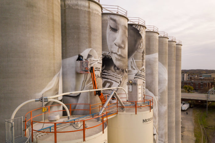 Photo by Rick Pepper - Aerial view of the in-progress Silo Art Project by Australian artist, Guido van Helten on the Ardent Mill grain silos at the gateway of Old Town, Mankato.