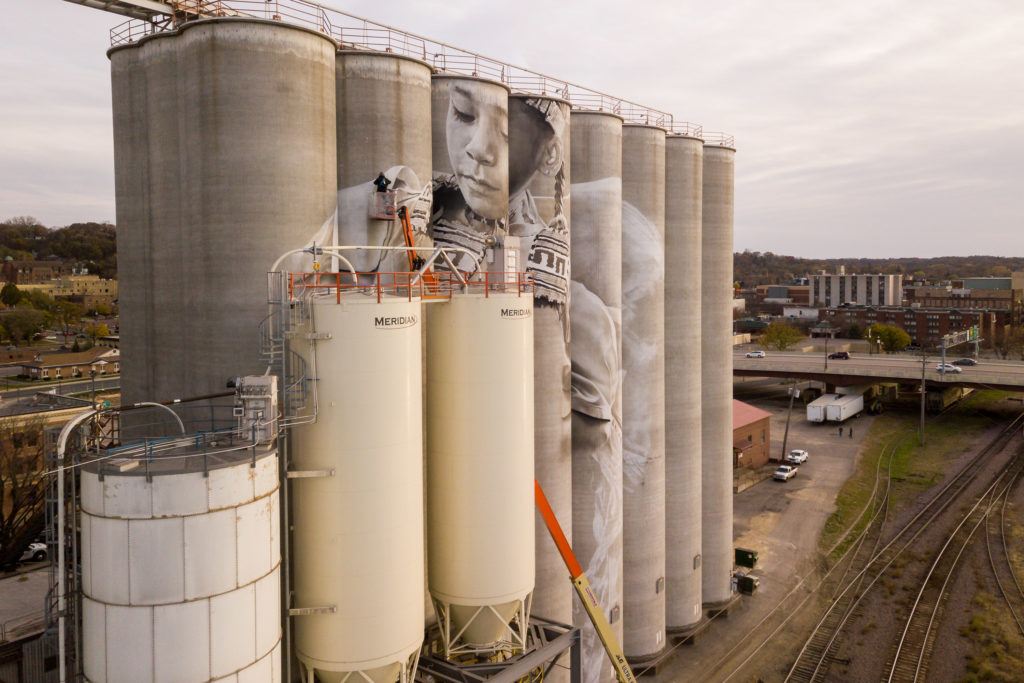 Photo by Rick Pepper - Aerial view of the in-progress Silo Art Project by Australian artist, Guido van Helten on the Ardent Mill grain silos at the gateway of Old Town, Mankato.