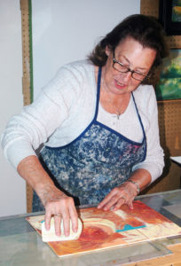 Photo by Don Lipps – Resident artist, Margie Larson working on a cold way painting.