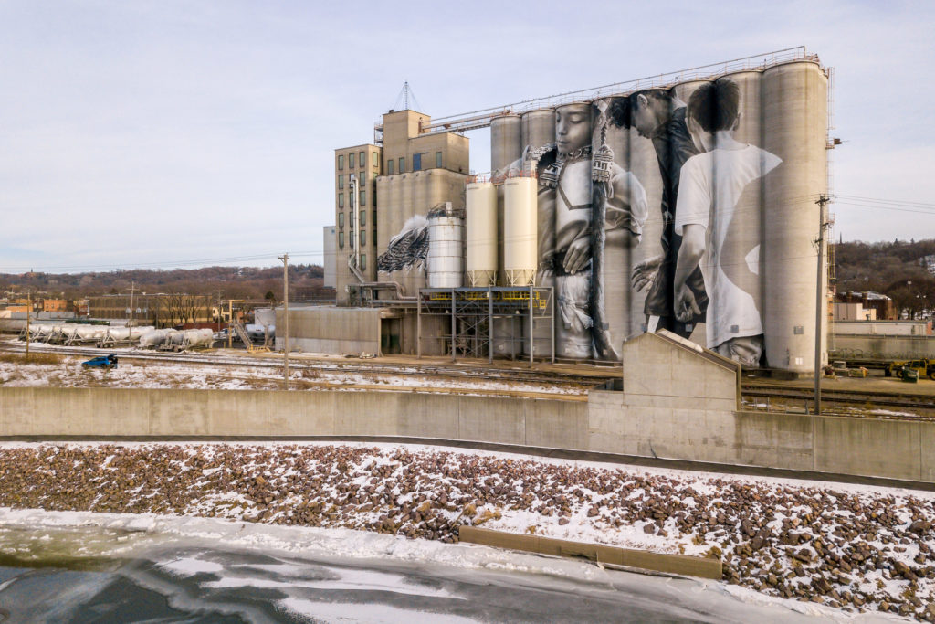 Photo by Rick Pepper - Aerial view of the in-progress Silo Art Project by Australian artist, Guido van Helten on the Ardent Mill grain silos at the gateway of Old Town, Mankato.