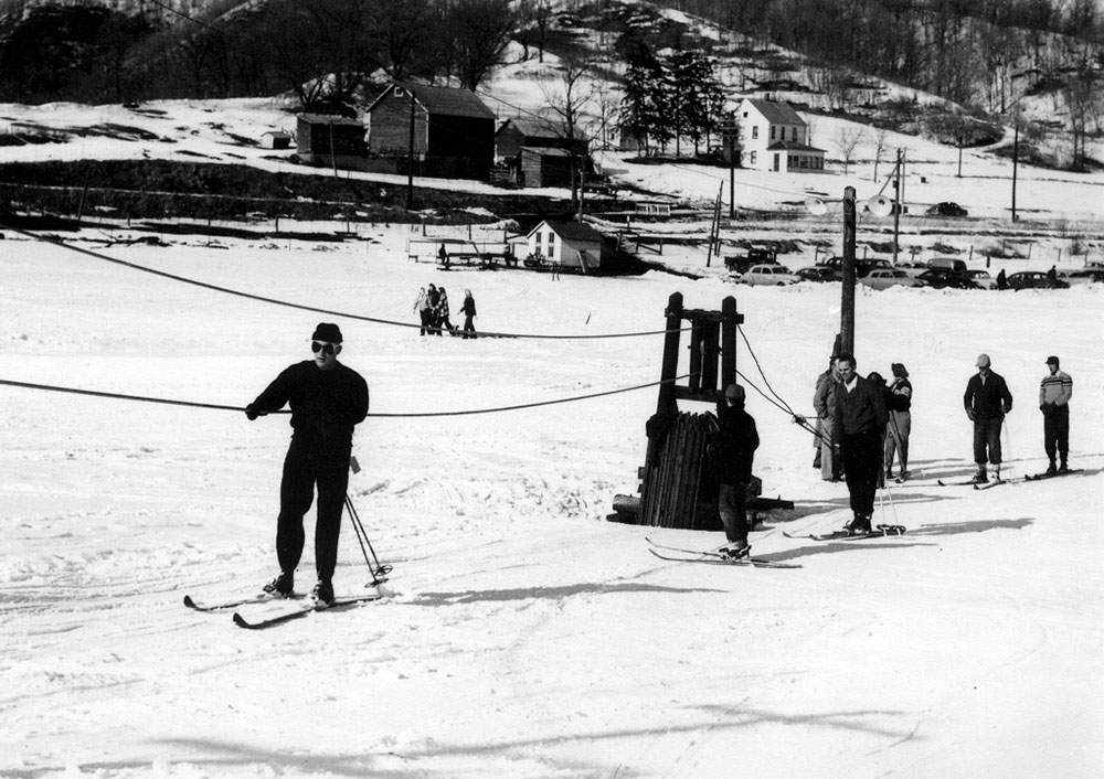 From History of the Red Jacket Valley by Julie A. Schrader - Skihaven, Winter 1952 - Shown in the foreground are skiers being pulled up the hill by the tow rope.