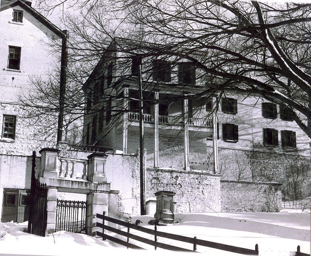 Photo courtesy of the Blue Earth County Historical Society - This photo shows the balconies of William’s home at the brewery. The stone pillars and iron gates still remain at the top of Rock Street.