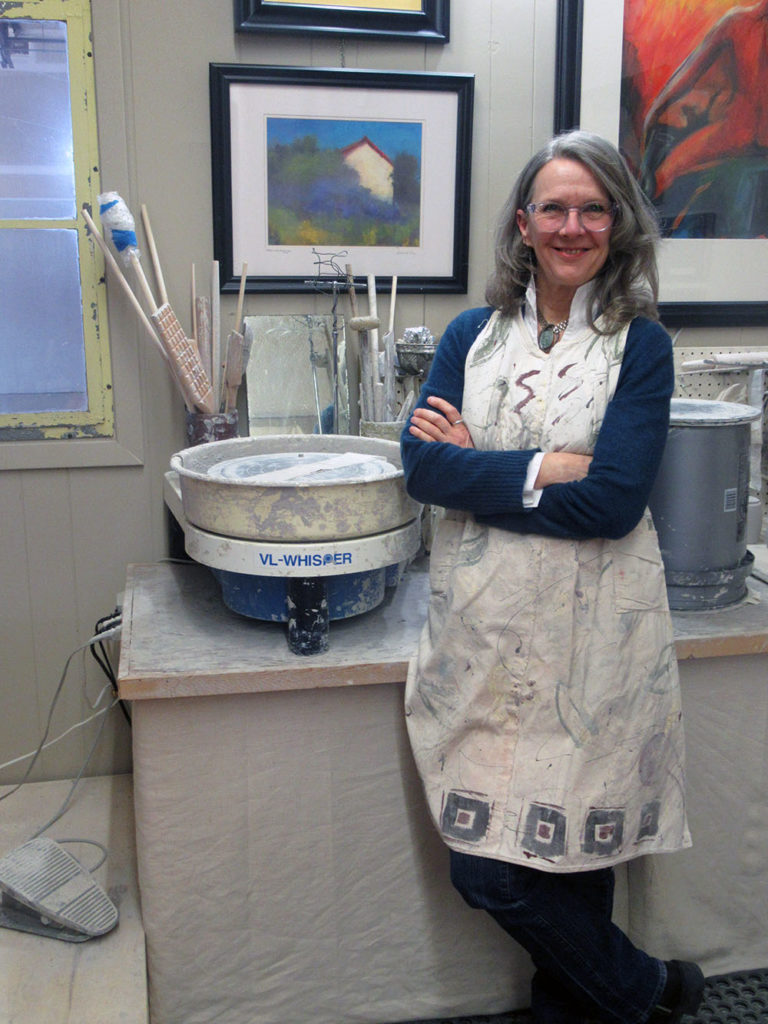 Photo by Grace Brandt - Ceramic Artist Michelle Kaisersatt next to her stand-up wheel in her studio in St. Peter