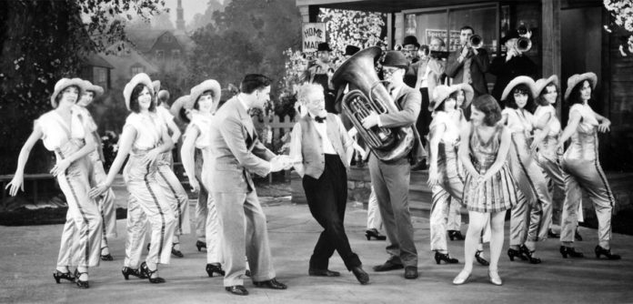 Photo courtesy Muriel Kuebler Berndt - Muriel and Barbara Kuebler in “50 Miles from Broadway,” one of the “short” pictures produced by Pathe Films to run in theaters between newsreels and the main feature. Barbara is third from the left and Muriel is to the immediate right of the tuba player.