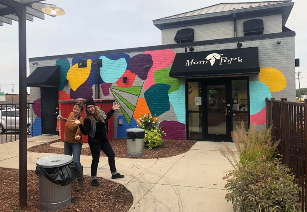 Photo by Rachael Jeager - Abby Daleki (right) and her friend Alison in front of her mural at Mom & Pop's Ice Cream Shop