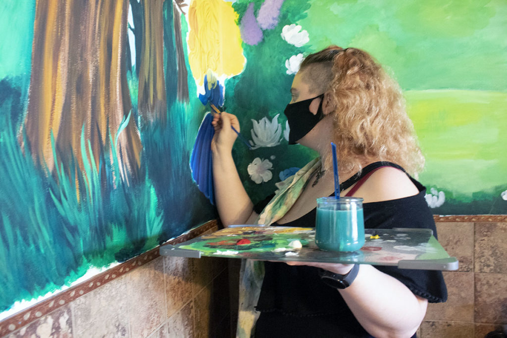 Photo by Rachael Jaeger - Jasmine Hancock at work on her Alice in Wonderland mural at CuriosiTea in North Mankato