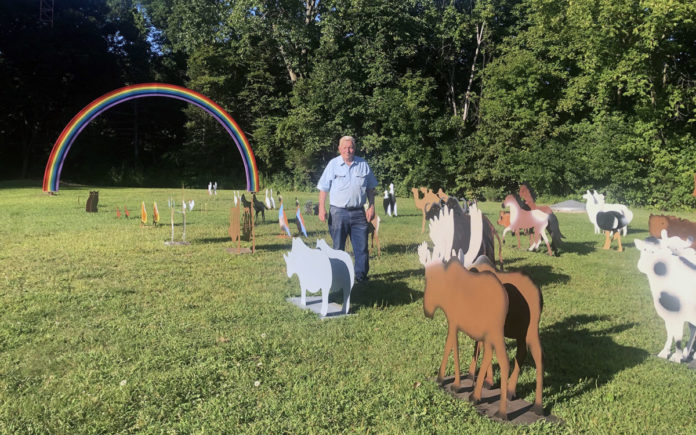 Photo by Mike Lagerquist - Arnie Lillo walks among the 46 pairs of animals created displayed 2-by-2 on his property. The ark he created from Colorado blue spruce will be placed under the rainbow.