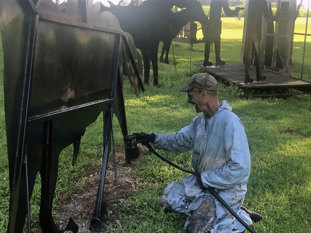 Photo by Mike Lagerquist - Denny Savick applies a new coat of black paint to a member of the Jesse James Gang display.