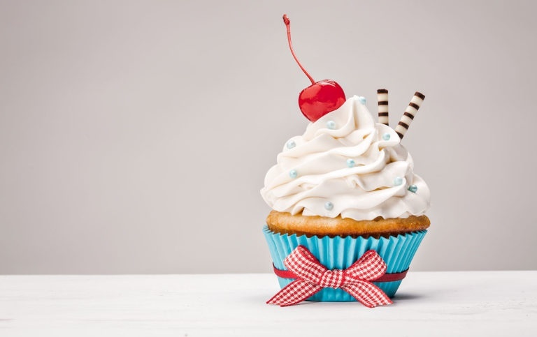 Cupcake with vanilla buttercream icing and a cherry on top.