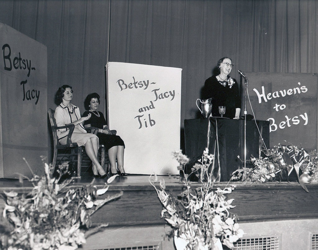 Photo courtesy of the Blue Earth County Historical Society - Maud Hart Lovelace addresses parents, teachers, librarians, and children in the Lincoln School auditorium on October 6, 1961. Seated are (L-R) Kathryn Hanson, President of the AAUW and Mary Lou Hanson, District #77 elementary school principal and daughter of Eleanor Wood Lippert [Dorothy].