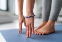 Yoga at home exercise in living room house - woman on fitness mat training stretching legs touching toes.