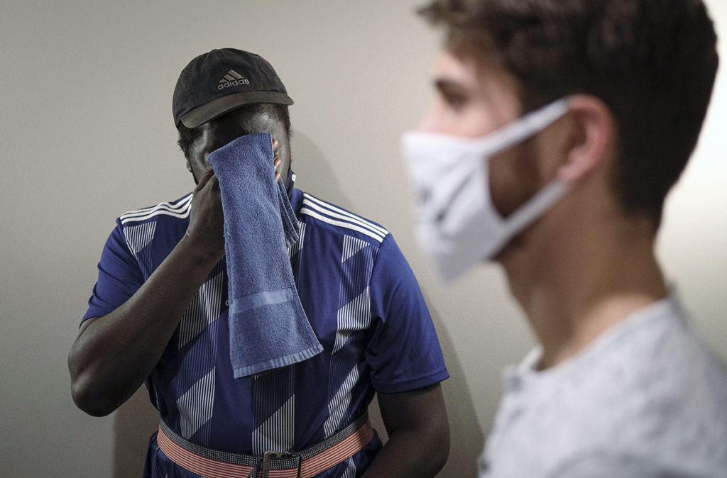 Photo by Casey Ek - Dang clears sweat from his forehead after walking a stretch of hallway outside his apartment. The 15-minute walks Murphy has built into his workouts tire him out to the same degree as a full day of pickup basketball or bike riding would have prior to his stroke.