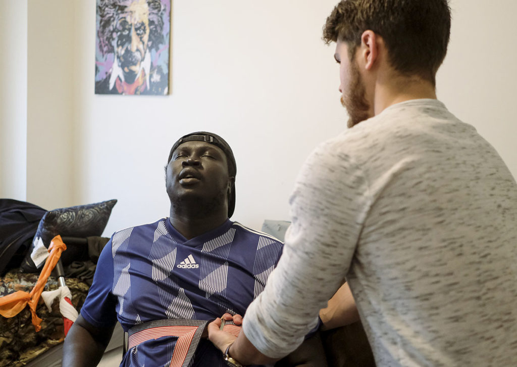 Photo by Casey Ek - On Jan. 8, a day after experiencing a seizure, Dang and Murphy had a rehabilitation session. Dang lets out a heavy breath after repeatedly standing from his wheelchair as part of his workout program.