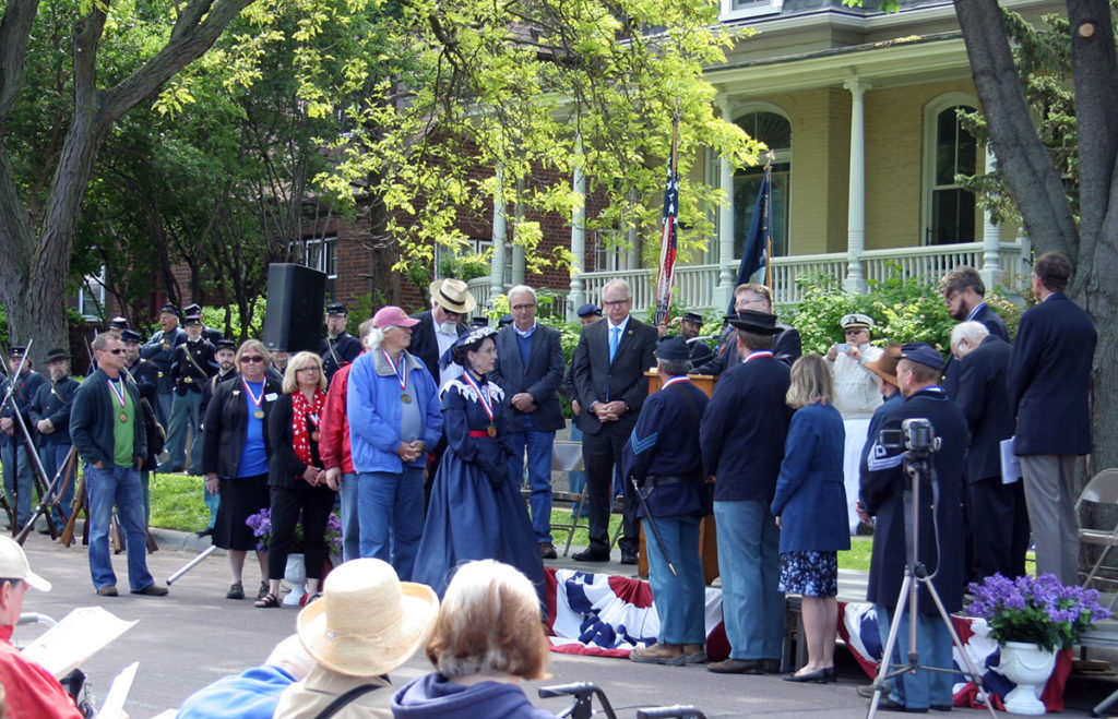 Submitted Photo - Dedication of the Boy in Blue Civil War Memorial in Lincoln Park, May 30, 2015. L-R: In front of stage: sculptor Alan Gibson, Boy in Blue committee members: Genette Carleton, Julie Schrader, David Johnson, John Ganey, Susan Hynes, Don Sandmeyer, James Olson, Shelley Harrison, Ron Goodrich and Arn Kind. On stage: MN State Representatives John Considine and Clark Johnson, On stage: U.S. Representative Tim Walz, speaking is Mayor Eric Anderson, Bryce Stenzel, Pastor Al Girtz and Darryl Sannes.