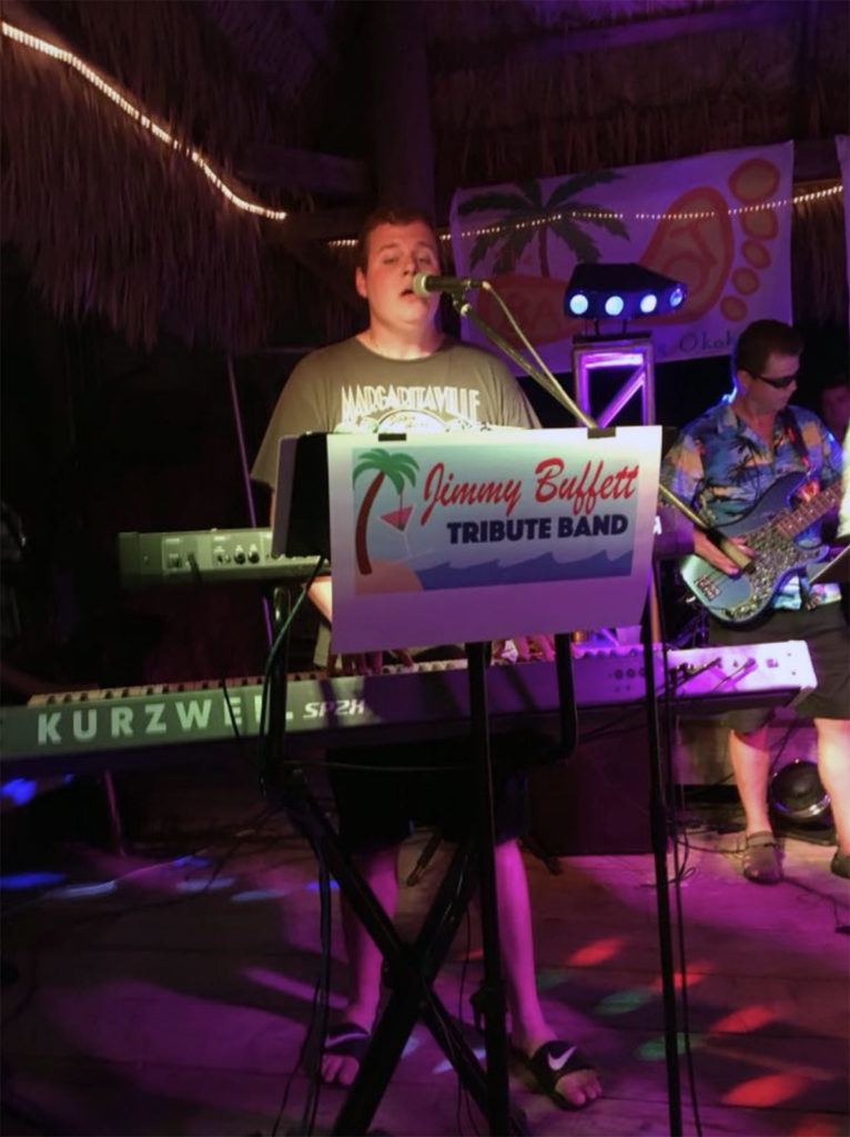 Submitted Image – Garrett Steinberg in front of the Jimmy Buffett Tribute Band, one of his many musical incarnations.