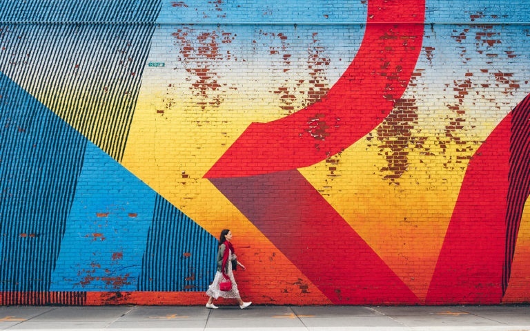 Young girl walking by wall with graffiti in New York